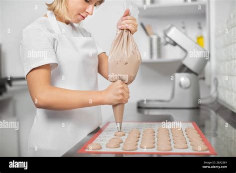 Une jeune confiserie féminine confectionne des macarons dans son