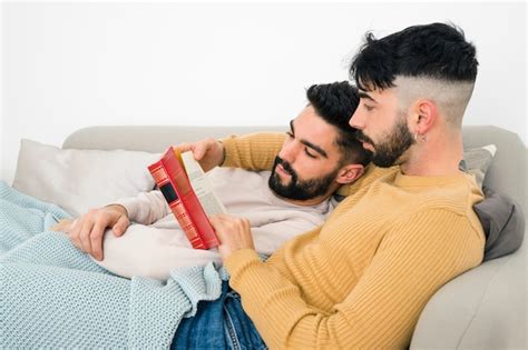Una pareja gay acostada en el sofá leyendo un libro en casa Foto Gratis