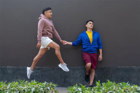 Casal gay de mãos dadas enquanto um deles pula ao ar livre Foto Premium