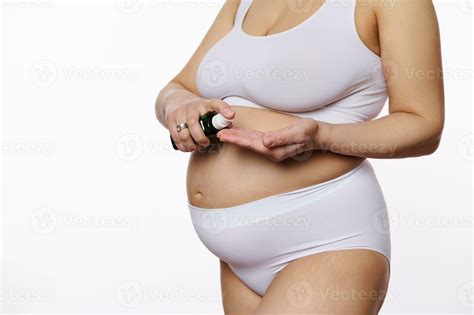 Close Up Of Pregnant Woman In White Lingerie Squeezing Some Massage Oil To Prevent Stretch