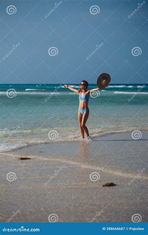Portrait Of Slim Woman Standing On The Beach In A Bikini And A Straw