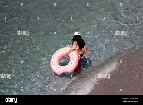 Femme Bronz E En Surpoids Dans Le Bikini Avec Anneau De Donut Gonflable Allant Par Le Sable Aux