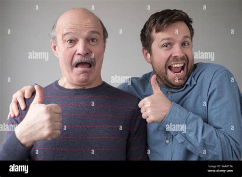 Two Caucasian Mature Men Father And Son Look At Camera Show Thumbs Up Expressing Positive