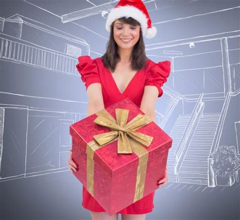Premium Photo Festive Brunette Giving A Gift Against Grey Vignette