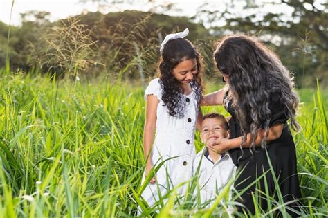 Família latina jovem mãe e filha olhando atentamente como seu filho jovem sorri brilhantemente