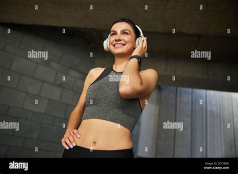Positive Delighted Brunette Woman Touching Her Headphones Stock Photo Alamy
