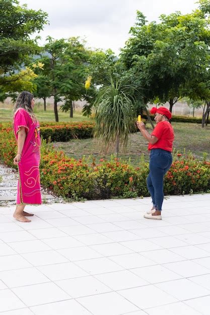 Mulher latina dançando enquanto a amiga tira fotos e vídeos o celular em um parque da cidade
