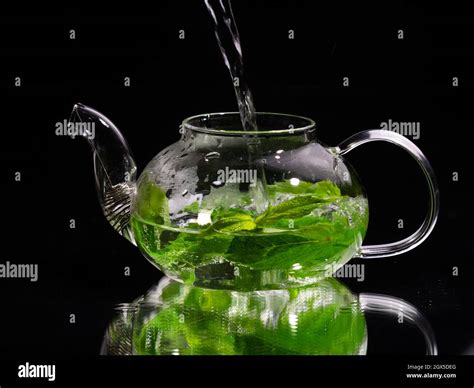 Pouring Hot Water Into A Glass Teapot On A Black Background Green Mint Tea Herbal Tea And