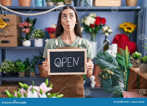 Jeune Brunette Travaillant Chez Fleuriste Tenant Une Enseigne Ouverte Faisant Du Poisson Visage