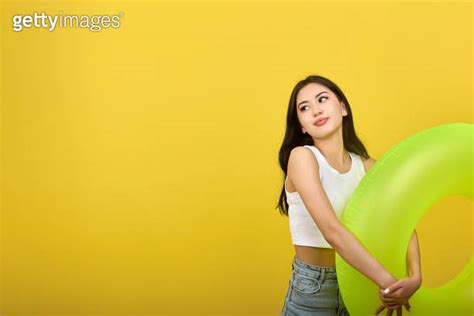 Slender young Asian brunette modestly holding an inflatable circle looking awa 이미지 2137500949