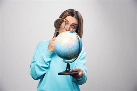 Fille Blonde En Sweat shirt Bleu Tenant Un Globe Et à La Recherche D une Destination Avec Loupe