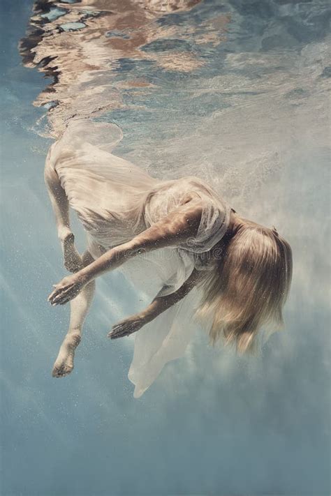 A Woman In A Dress Swims Underwater As If Floating In Zero Gravity