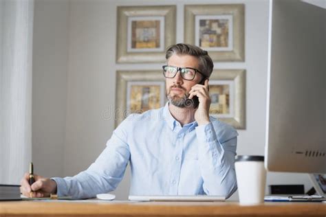 Empresario De Mediana Edad Sentado En Casa Y Usando Smartphone Y