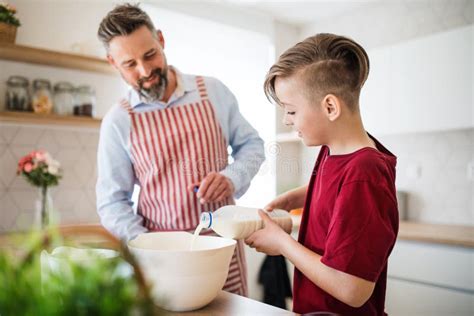 Mature Father With Small Son Indoors In Kitchen Making Pancakes Stock
