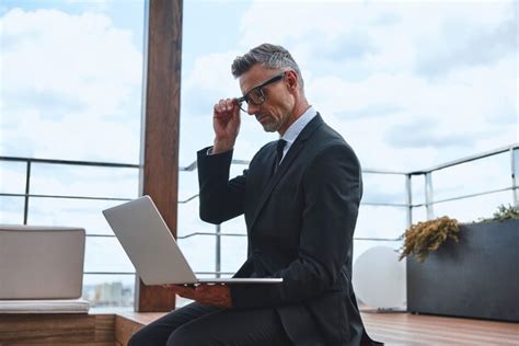 Premium Photo Confident Mature Man Working On Laptop While Standing On The Rooftop Terrace