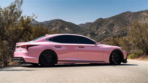 A Light Pink Lexus Model Ls500 With Black Wheels Parked On A Sunny Road