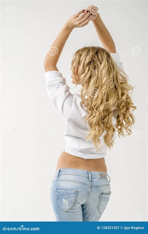 Blonde Hermoso Joven De La Muchacha En Una Camisa Blanca Y Vaqueros Con Huecos Imagen De Archivo