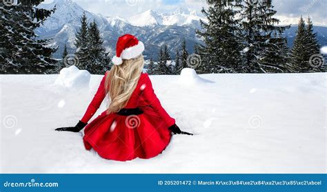 Merry Christmas Beautiful Blonde Woman In Red Dress And Santa Clause Hat On A Background Of