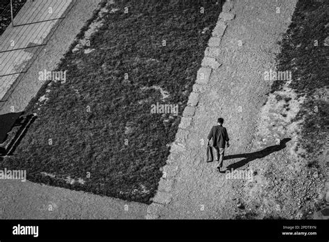 Old Man Walking On An Alley Next To The Street With His Shadow To The