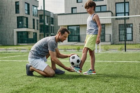 Retrato de vista lateral del joven padre enseñando fútbol a su hijo en