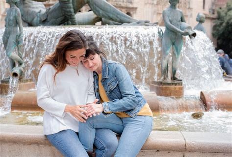 Una joven pareja de lesbianas hispanas sentada en una fuente en Valencia concepto gay y lésbico