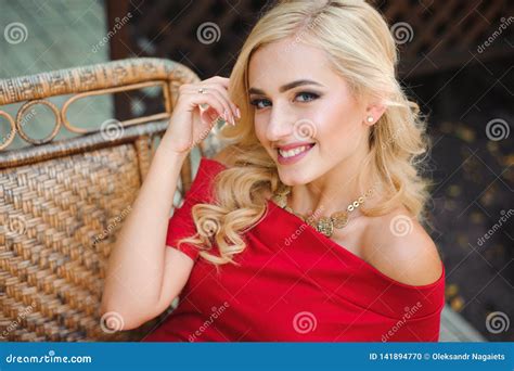 Fashionable Attractive Blonde Woman In Red Dress Sitting On Chair Stock Photo Image Of Legs
