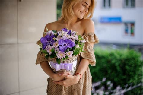 Een Jonge Glimlachende Blonde Houdt Zich In Haar Handen Aan De Wieksmand Gebonden Met Lint En
