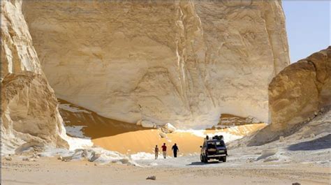 People Are Standing In Front Of A Truck On The Side Of A Mountain With Snow