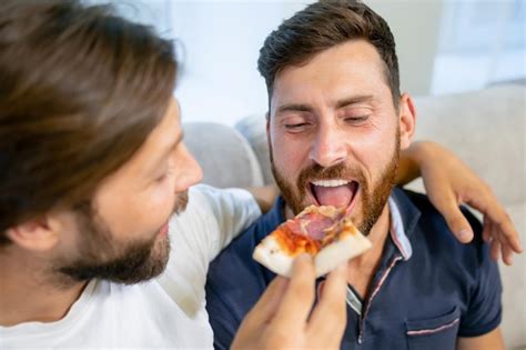 Homem bonito família gay sentado no sofá comendo pizza juntos atraente casal masculino romântico