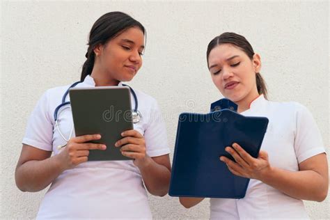 Two Latina Nurses Looking At Clipboard While Working In The Hospital Stock Photo Image Of