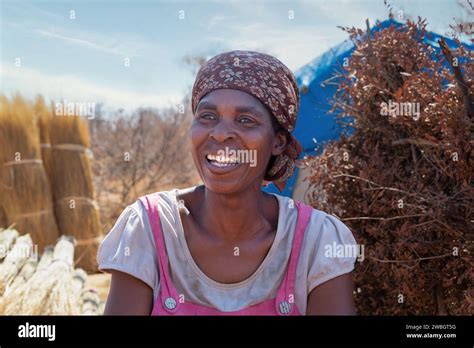 Smiling African Woman In The Village Shack In The Background Working