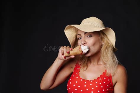 Belle Femme Blonde Européenne En Chapeau D été Et Maillot De Bain Rouge En Mangeant Une