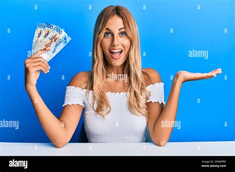 Schöne blonde junge Frau hält 100 schweizer Franken Banknoten feiern