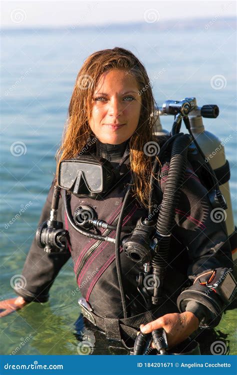 Female Scuba Diving Instructor Standing In Water Wearing A Dry Suit A