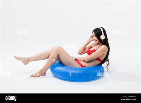Side View Of Woman In Bikini Sitting On A Tube Listening To Music Stock Photo Alamy