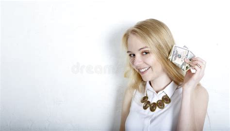 Blonde Holds Dollar Bills Near Her Ear And Listens With A Satisfied Smile To The Crunch Of