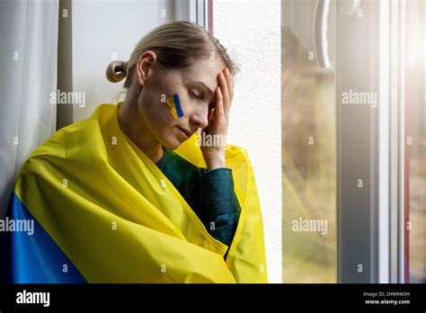 triste femme inquiète avec le drapeau de l ukraine assis sur le seuil