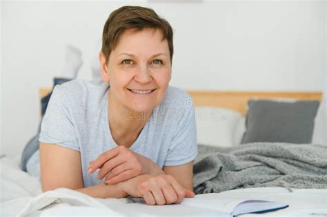 Middle Age Blonde Woman Reading Book Lying On The Bed At Home Stock Photo Image Of Home