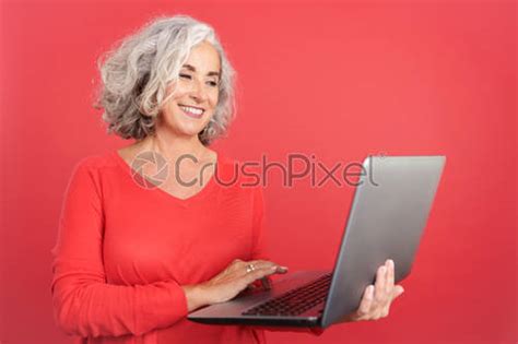 Smiley Mature Woman Standing And Using A Laptop Stock Photo Crushpixel