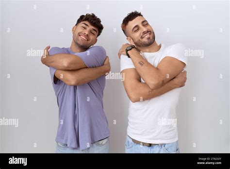 Homosexual Gay Couple Standing Over White Background Hugging Oneself Happy And Positive Smiling