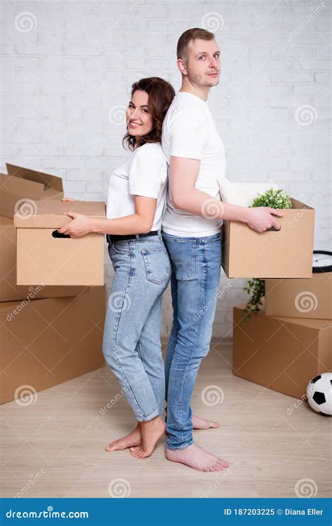 Full Length Portrait Of Couple Holding Cardboard Boxes Ready To Moving