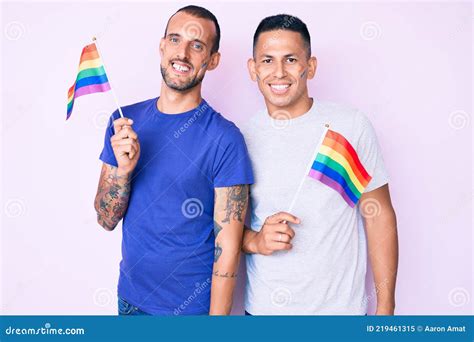 Joven Gay Pareja De Dos Hombres Sosteniendo Arco Iris Lgbtq Banderas Juntos Mirando Positivo Y