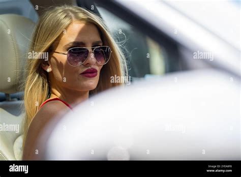 A Gorgeous Blonde Woman Playfully Flirts With Her Lover Inside Her Sleek White SUV With A