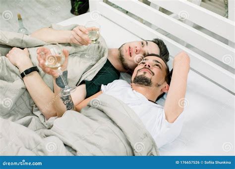 Dos Tipos Guapos Beben Vino Blanco Tumbado En La Cama En Casa Joven Pareja Gay Tendida Bajo