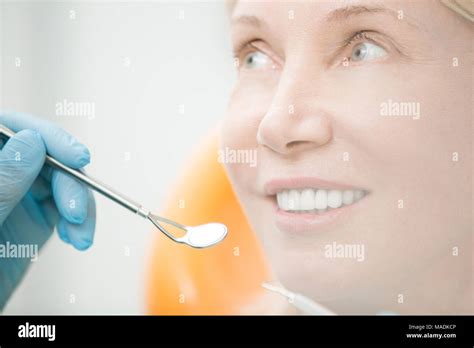 Healthy Mature Woman With Toothy Smile Looking At Dentist With Mirror