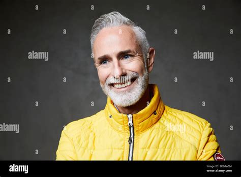 Happy Mature Man With Gray Hair Standing In Front Of Grey Background
