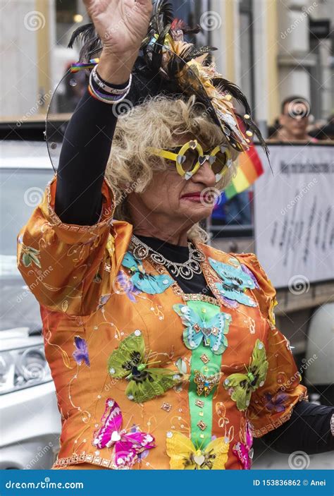 A An Older Woman In An Ornage Costume Attending The Gay Pride Parade Also Known As