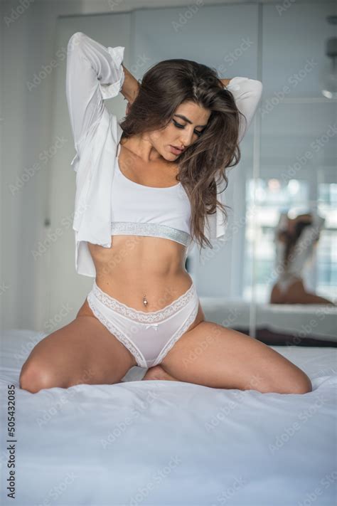 Attractive Sexy Brunette In White Lingerie Posing Provocatively Near A Mirror Studio Shot