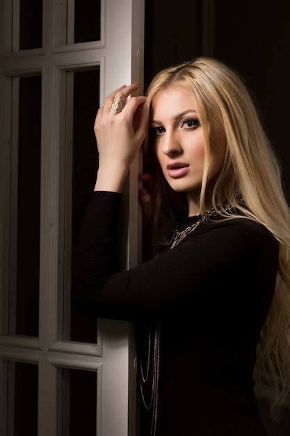 Premium Photo Tender Blonde Woman With Long Lush Hair Posing At The White Door With Shadow On