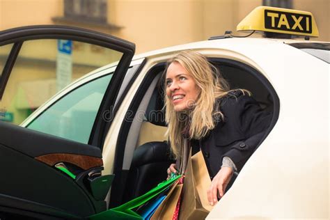La Jeune Femme Sort Du Taxi Avec Des Paniers Image Stock Image Du Pluie Blonde 100674913
